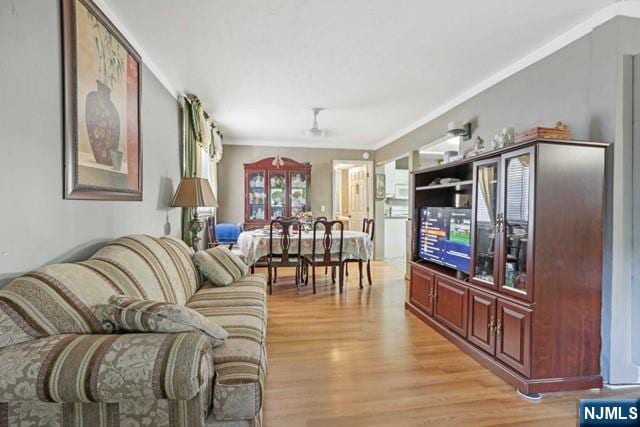 living room with ornamental molding and light wood-style flooring
