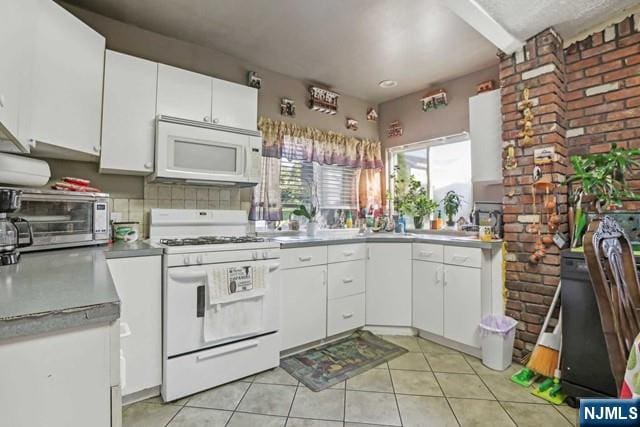 kitchen featuring a toaster, light tile patterned floors, white cabinets, light countertops, and white appliances