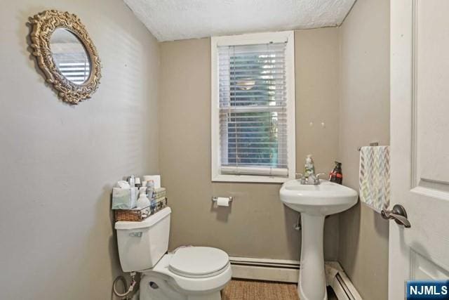bathroom featuring baseboards, baseboard heating, toilet, and a textured ceiling
