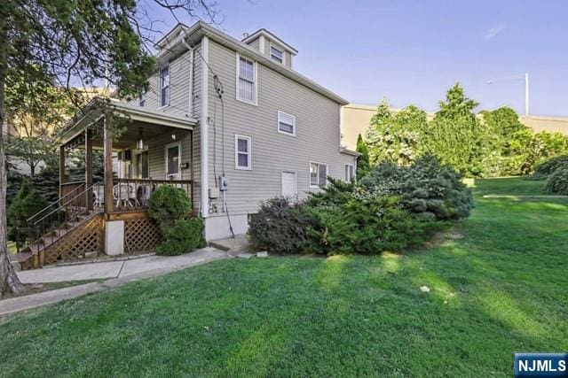 view of side of property with a porch and a yard