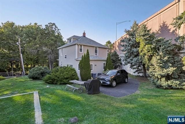rear view of property with a yard and a chimney