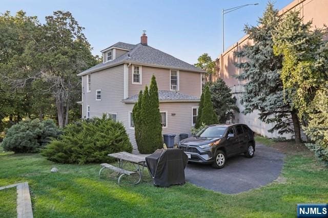 view of side of home with a lawn and a chimney