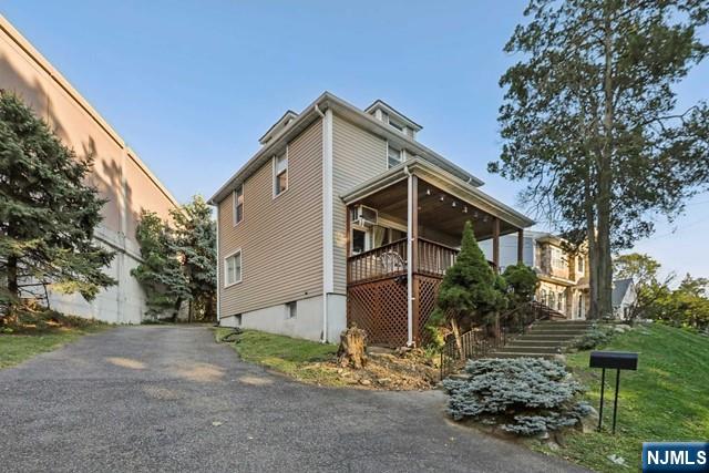 view of side of property with stairs, driveway, and covered porch