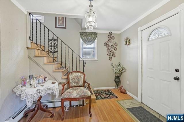 entryway featuring crown molding, wood finished floors, baseboards, stairway, and a chandelier