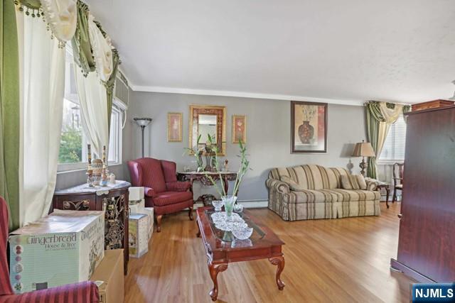 living room with ornamental molding, baseboard heating, and wood finished floors