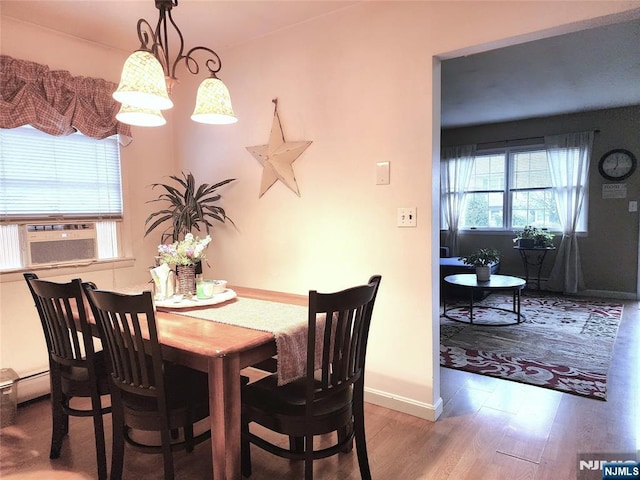 dining space featuring wood finished floors, cooling unit, and baseboards