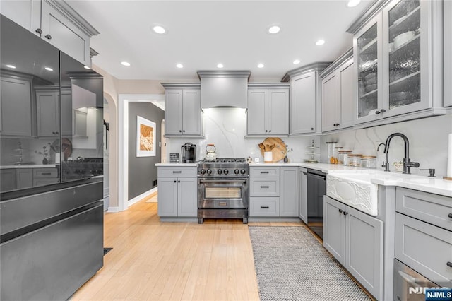 kitchen with gray cabinetry, premium range hood, high end stainless steel range oven, and dishwasher