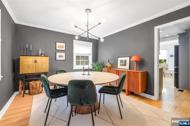 dining space with a notable chandelier, light wood finished floors, baseboards, visible vents, and ornamental molding