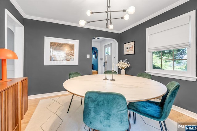 dining area featuring arched walkways, ornamental molding, and light wood-type flooring