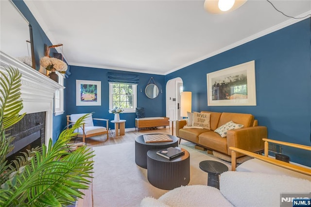 living room with arched walkways, ornamental molding, wood finished floors, and a fireplace
