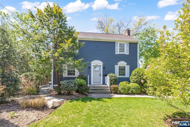 colonial inspired home with a chimney and a front lawn