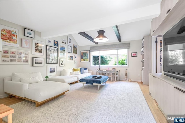 living area with baseboards, lofted ceiling with beams, and light wood-style floors