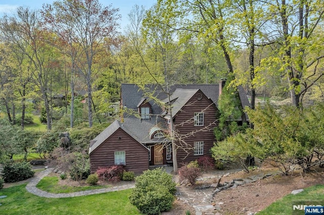 log-style house with roof with shingles, a chimney, and a front yard