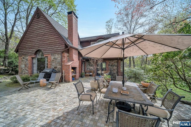 view of patio with grilling area, outdoor dining area, and an outdoor brick fireplace