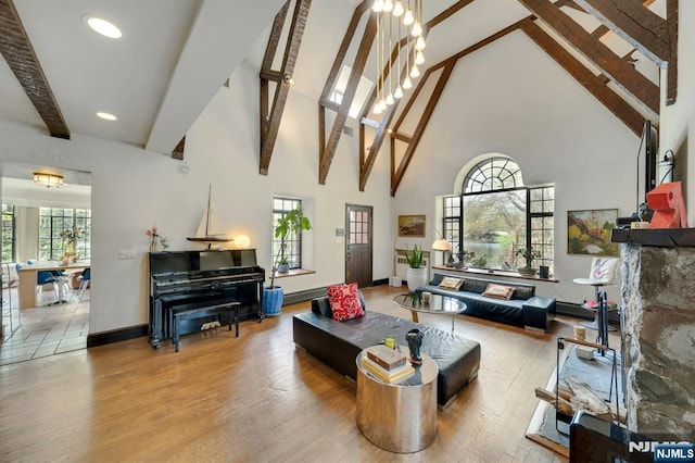 living room with wood finished floors, baseboards, beam ceiling, and high vaulted ceiling