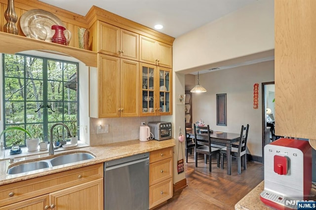 kitchen with glass insert cabinets, dark wood-type flooring, light stone counters, a sink, and dishwasher