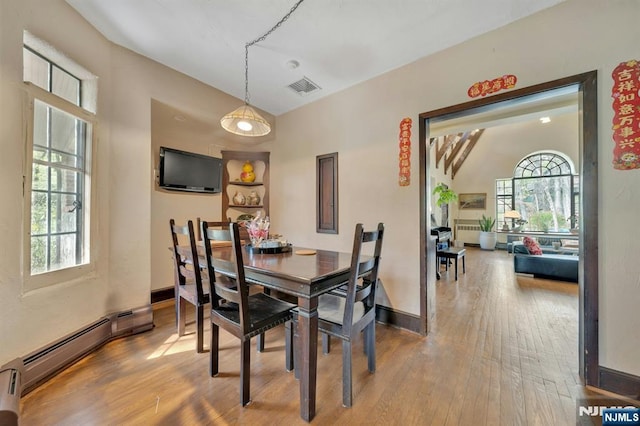 dining room featuring baseboards, a baseboard radiator, hardwood / wood-style flooring, and visible vents