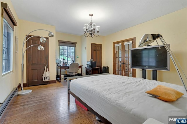 bedroom with wood finished floors, baseboards, a baseboard heating unit, french doors, and a notable chandelier
