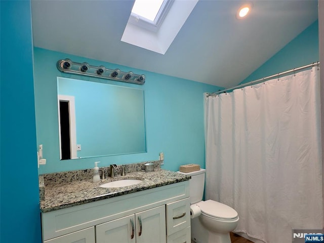 full bathroom with vanity, vaulted ceiling with skylight, and toilet
