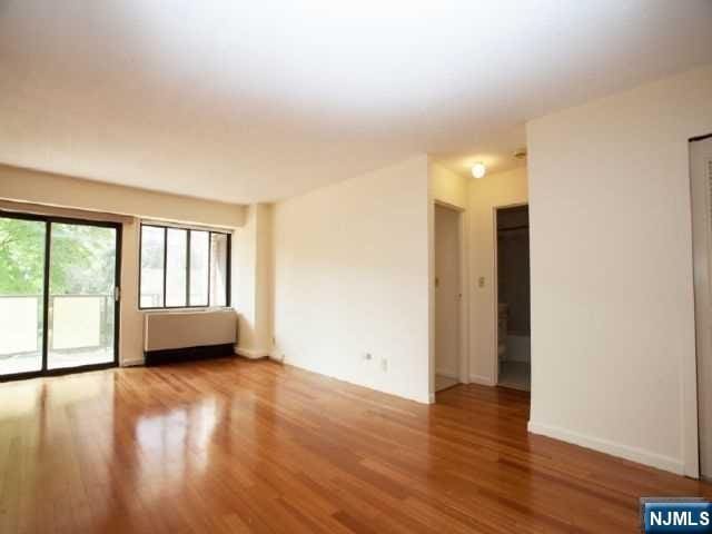 spare room with baseboards and wood finished floors
