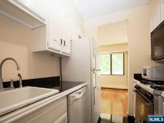 kitchen featuring a sink, white cabinetry, and white appliances