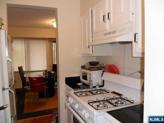 kitchen with light countertops, white cabinets, and white appliances