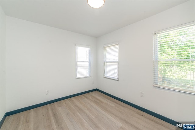 spare room with baseboards and light wood-type flooring