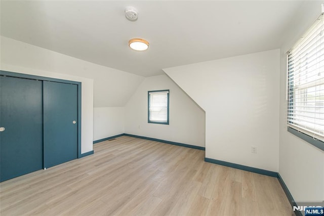 bonus room featuring baseboards, vaulted ceiling, and light wood-style flooring