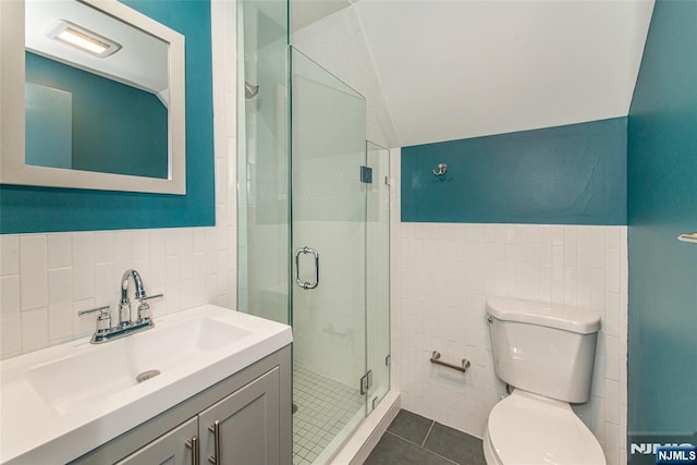 full bath featuring tile patterned flooring, toilet, tile walls, a shower stall, and vaulted ceiling