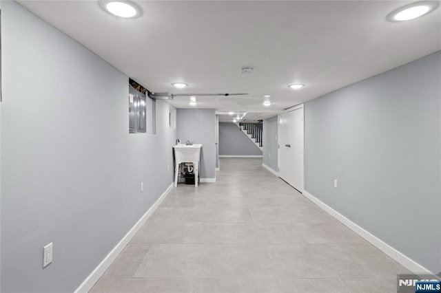 finished basement featuring baseboards, a sink, recessed lighting, and stairway