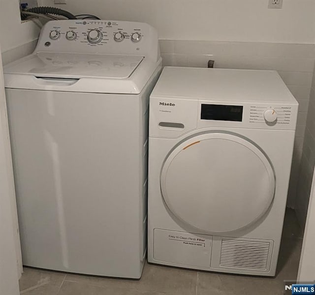 laundry room featuring light tile patterned floors, laundry area, and independent washer and dryer