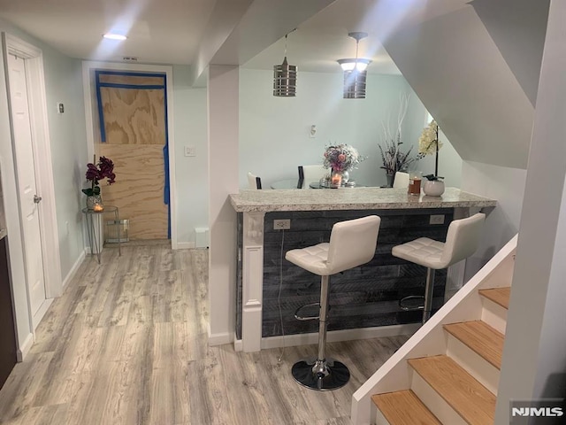 bar with baseboards, indoor bar, and wood finished floors