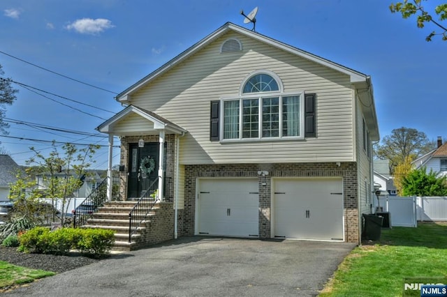 view of front of property with fence, an attached garage, a front lawn, brick siding, and driveway