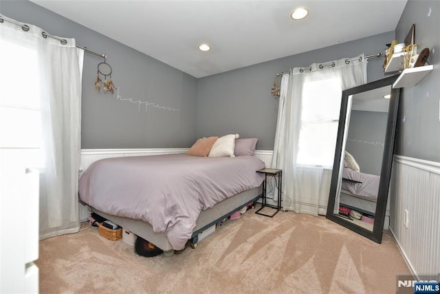 carpeted bedroom with recessed lighting and a wainscoted wall
