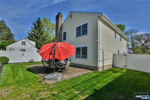 rear view of house featuring a fenced backyard, a gate, a patio, and a lawn