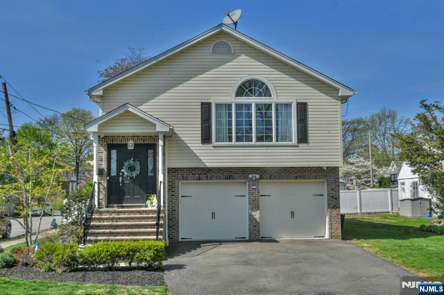 view of front of house featuring fence, an attached garage, a front lawn, brick siding, and driveway