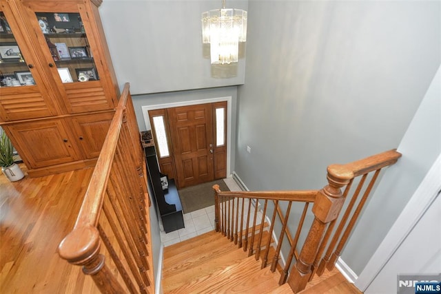 entrance foyer featuring baseboards, a chandelier, light wood finished floors, and stairway