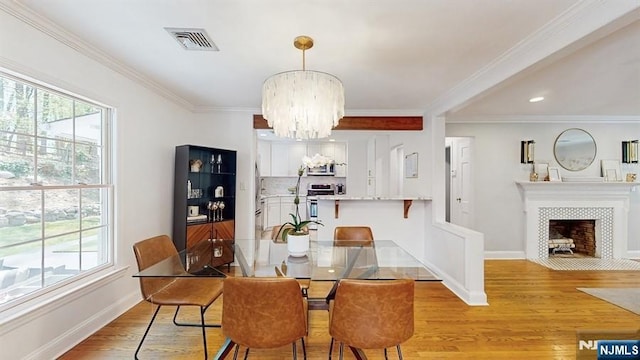 dining room featuring visible vents, light wood-style flooring, a notable chandelier, and a wealth of natural light