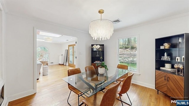 dining room with an inviting chandelier, light wood finished floors, baseboards, visible vents, and ornamental molding