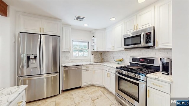 kitchen with white cabinets, appliances with stainless steel finishes, decorative backsplash, and a sink