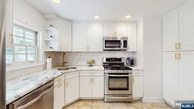 kitchen with a sink, decorative backsplash, white cabinets, and stainless steel appliances