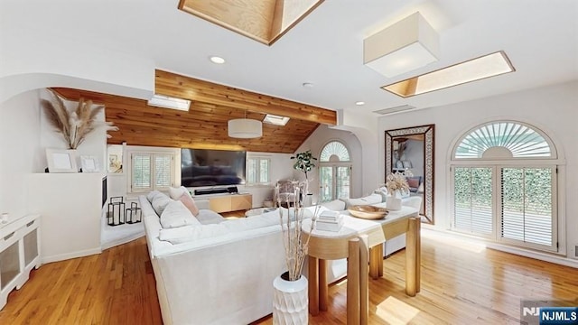 living room featuring light wood-style floors, arched walkways, recessed lighting, and lofted ceiling