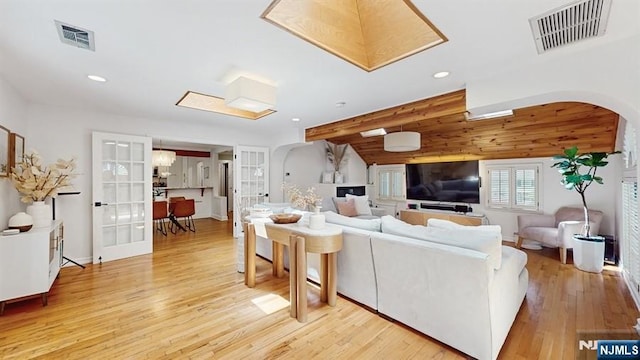 living area with visible vents, arched walkways, recessed lighting, and light wood-type flooring