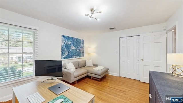 living room featuring baseboards, light wood finished floors, and visible vents