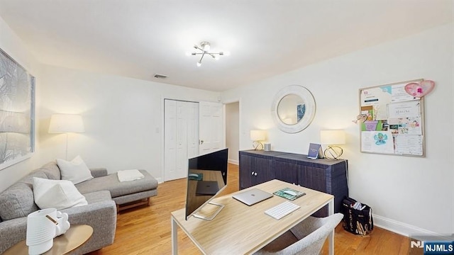 office area featuring baseboards, light wood-type flooring, and visible vents