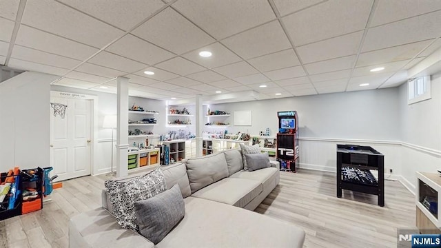 living area featuring recessed lighting, a drop ceiling, light wood-style flooring, and a wainscoted wall