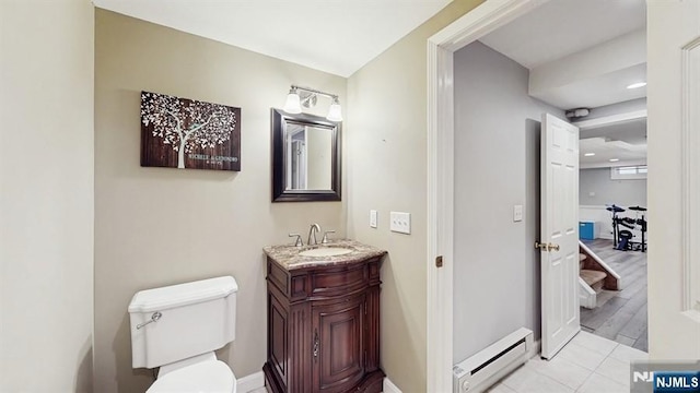 half bath featuring vanity, toilet, tile patterned floors, baseboards, and a baseboard radiator