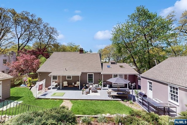 rear view of property with a chimney, a lawn, a wooden deck, a fenced backyard, and outdoor lounge area