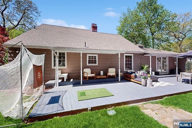 rear view of house with an outdoor living space, a wooden deck, and a chimney