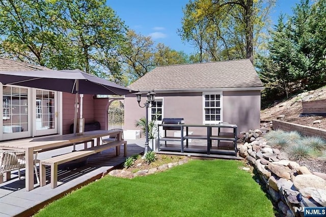 back of house featuring a lawn, roof with shingles, stucco siding, and a deck